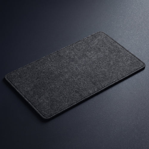 A dark gray felt desktop pad with rounded corners, shown at an angle on a dark gray textured background.